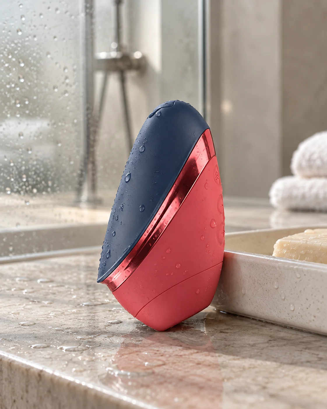 Blue/Red Womanizer Next Liberty with water droplets in a softly lit bathroom