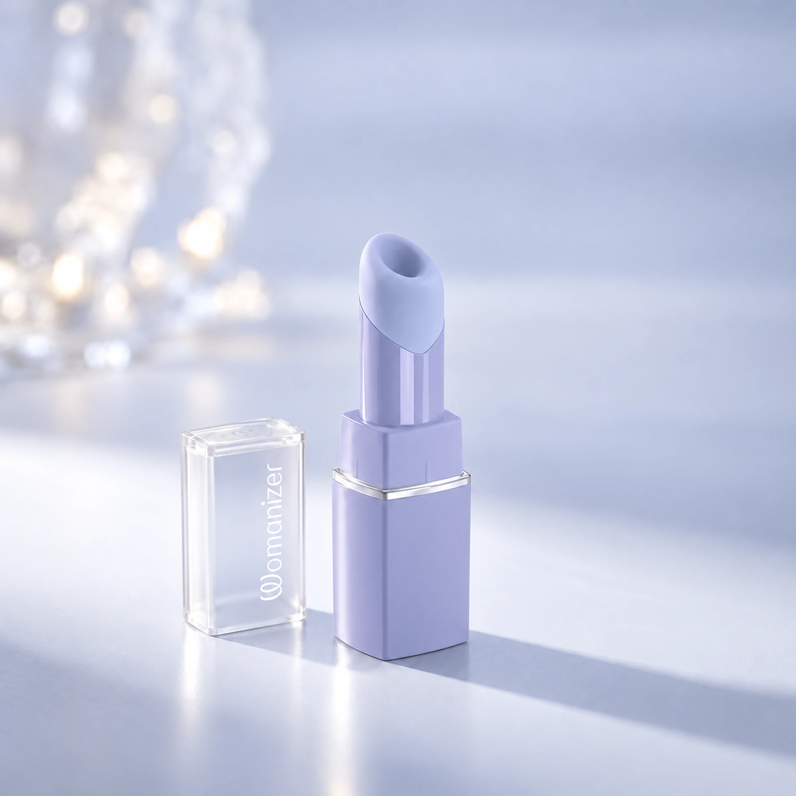 Womanizer Beauty in Lilac, with clear cap beside the device