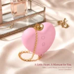 Blush-pink Cupid's Heart suction stimulator on ivory satin beside a mirrored vanity box.