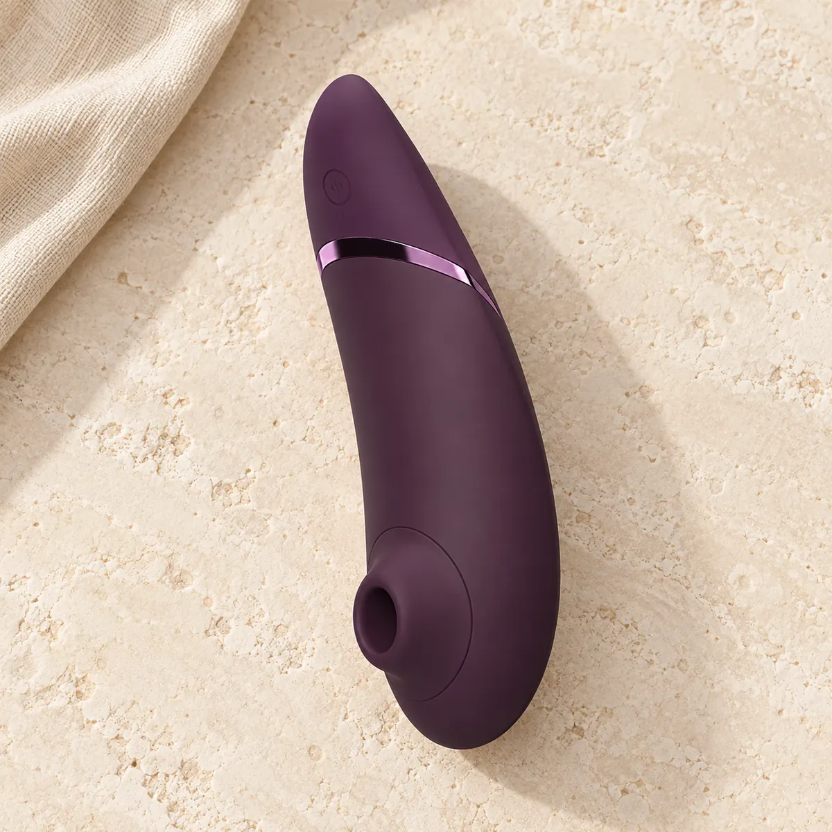 Womanizer Next in dark purple on warm stone with pale linen