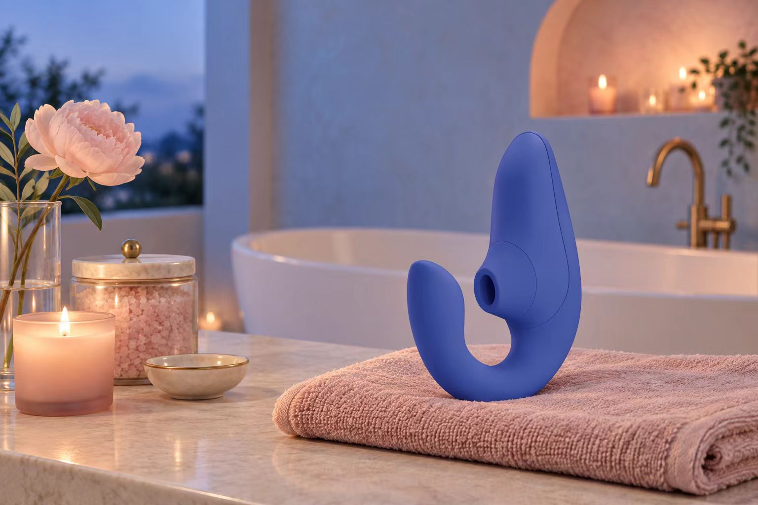 Womanizer Blend on pink towels beside a warmly styled bath