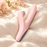 Secret Language blush pink dual-arm vibrator, side view in a softly lit scene.
